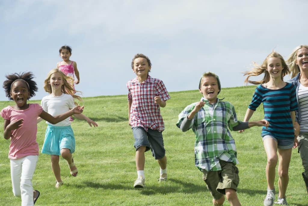 A group of children running across a grass field.