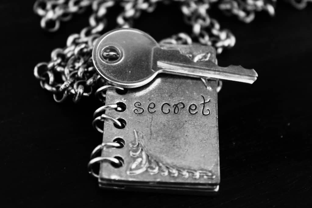 Silver chain and pendant in the shape of a book , ingraved with the word ‘secret’ , silver key