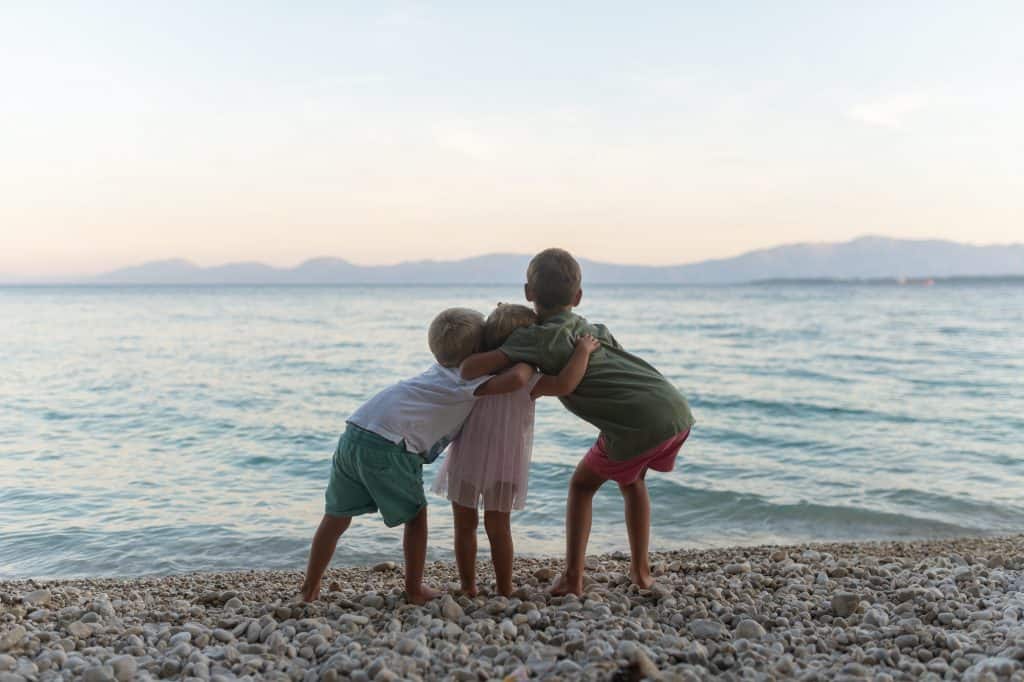 Three sibling hugging on the beach