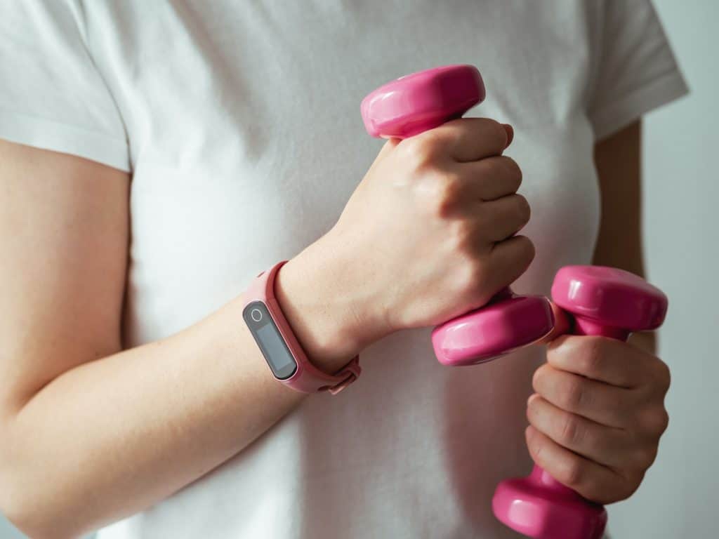 Woman with fitness tracker and barbells