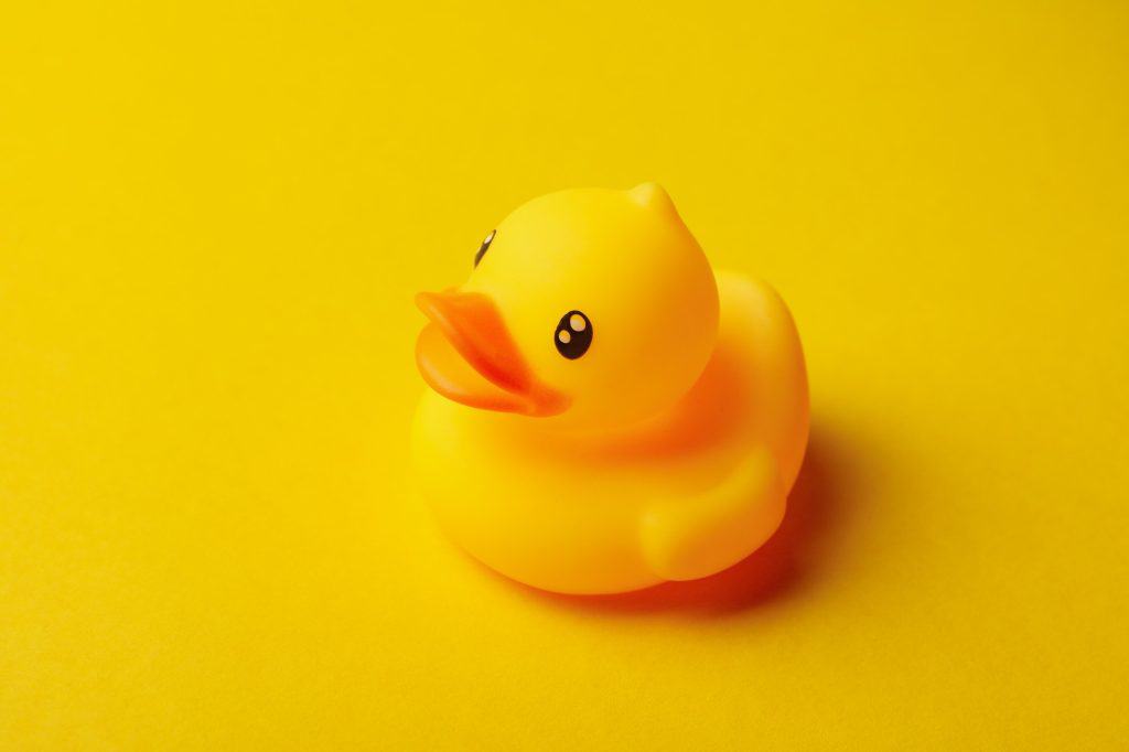 Cute rubber duck on yellow background, close up