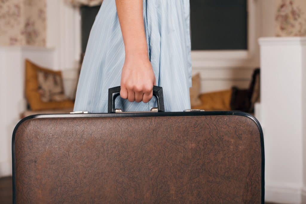 Female hand holding suitcase.