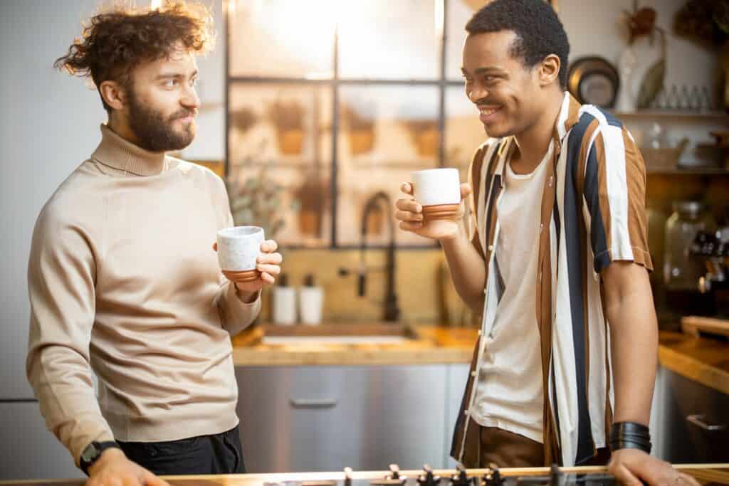 Two men talking and drinking coffee on kitchen at home